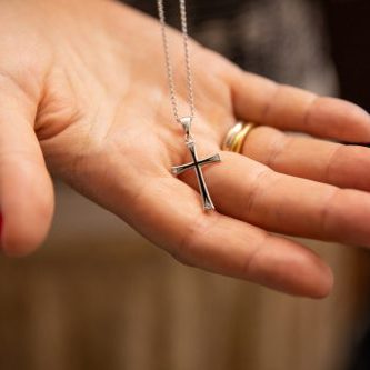 Orthodox christenings of a child, a cross in his father's hand. Macro