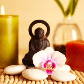 Spa still life buddha statue and river rock, bamboo in vase, and candles, and orchid flower